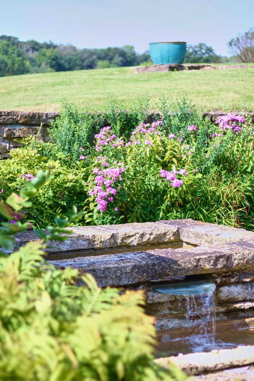 Natural stone waterfall with lush planting bed water feature